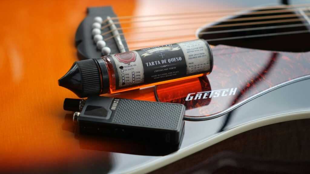 Electronic cigarette and liquid bottle on a Gretsch guitar, emphasizing modern lifestyle.