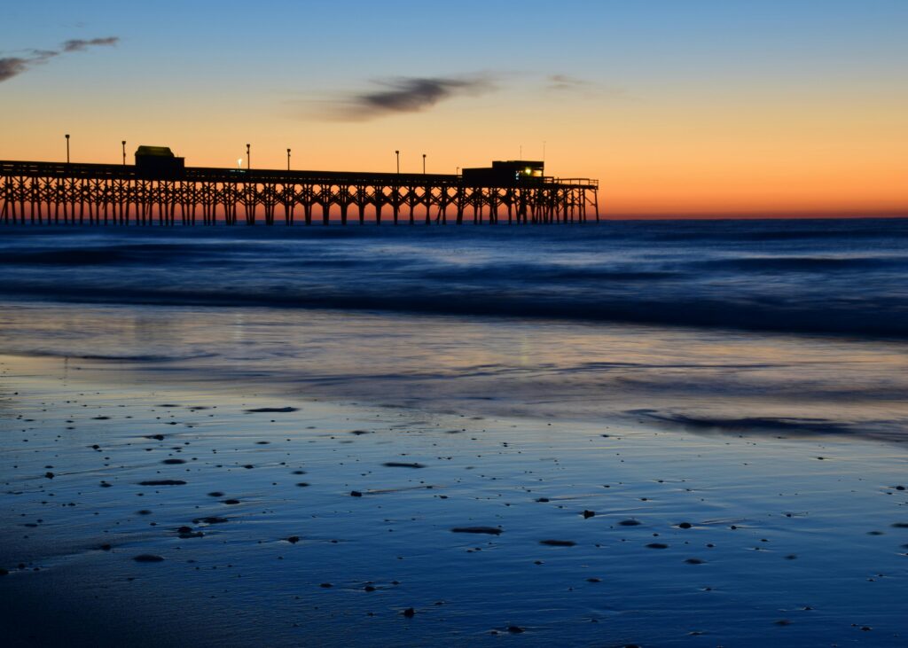 Silhouette of Myrtle Beach pier against a vibrant sunset sky.